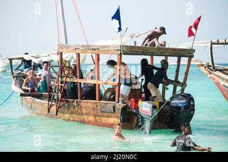 Sansibar, Tansania - Januar 02,2022: Touristen kehren mit dem Boot von der Insel Sansibar zum Strand der Pongwe Bay zurück. Stockfoto