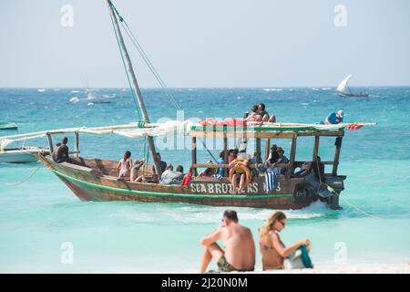 Sansibar, Tansania - Januar 02,2022: Touristen kehren mit dem Boot von der Insel Sansibar zum Strand der Pongwe Bay zurück. Stockfoto