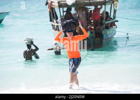 Sansibar, Tansania - Januar 02,2022: Touristen kehren mit dem Boot von der Insel Sansibar zum Strand der Pongwe Bay zurück. Stockfoto