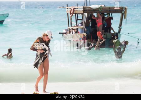 Sansibar, Tansania - Januar 02,2022: Touristen kehren mit dem Boot von der Insel Sansibar zum Strand der Pongwe Bay zurück. Stockfoto