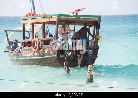 Sansibar, Tansania - Januar 02,2022: Touristen kehren mit dem Boot von der Insel Sansibar zum Strand der Pongwe Bay zurück. Stockfoto