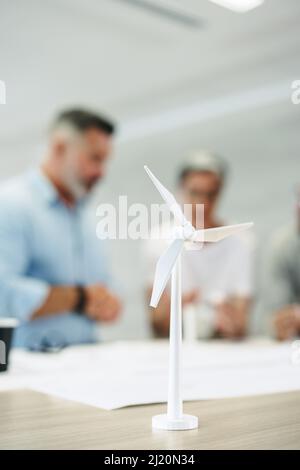 Eine Gruppe kreativer Ingenieure, die mit 3D Windenergieanlagenmodellen in einem modernen Büro arbeiten. Team von innovativen Geschäftsleuten Brainstorming während der Arbeit an einem Stockfoto