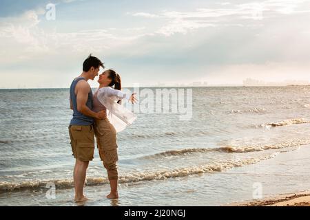 Ein junges Paar umarmen, das barfuß am Meer steht - Stock photo Stockfoto