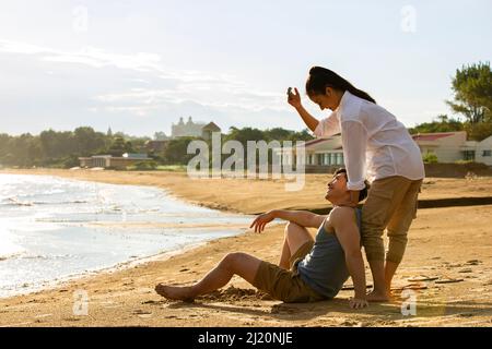 Ein junges Paar, das an einem Sommerstrand fotografiert - Stockfoto Stockfoto