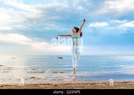 Junge Frau praktiziert Yoga allein an einem Sommerstrand - Stock Foto Stockfoto