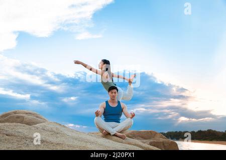 Paare, die Yoga auf den Felsen der Insel praktizieren - Stock photo Stockfoto