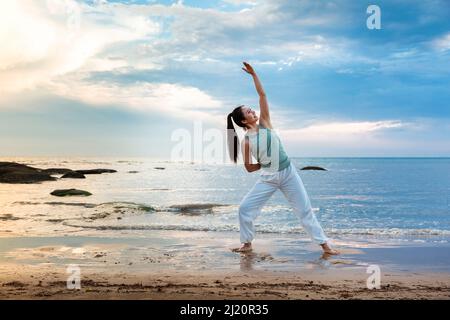 Junge Frau praktiziert Yoga allein an einem Sommerstrand - Stock Foto Stockfoto