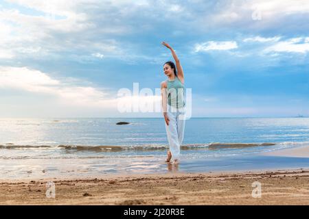 Junge Frau praktiziert Yoga allein an einem Sommerstrand - Stock Foto Stockfoto