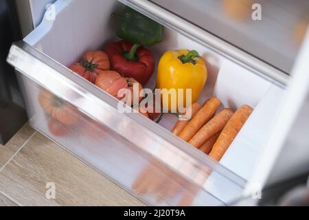 Frisches Gemüse in der Schublade des geöffneten Kühlschranks. Stockfoto