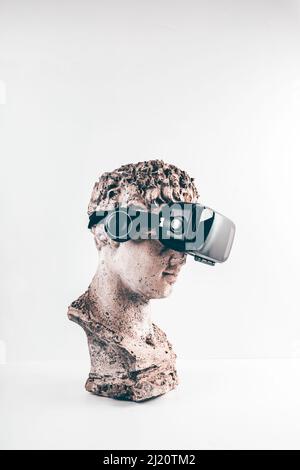 Alte Statue mit VR-Brille auf weißem Hintergrund. Konzept von Kunst und Virtual Reality. Stockfoto