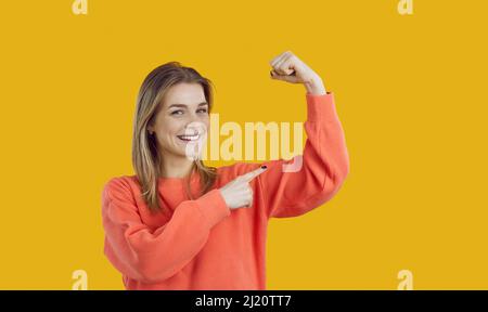 Glückliche schöne junge Frau lächelt und biegt ihren Arm zur Illustration Girl Power Concept Stockfoto