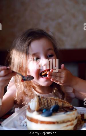 Kinderparty in Mützen feiert Geburtstag mit Kuchen und Ballons zu Hause. Stockfoto