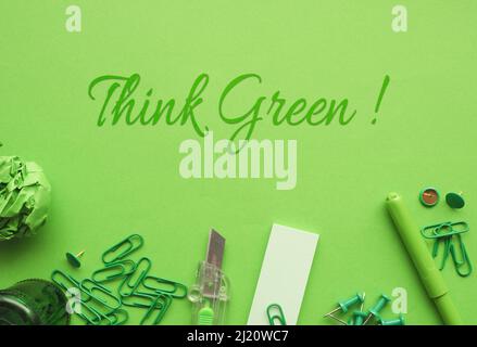 Text Think Green mit Büroutensilien auf grünem Papier, Umweltkonzept Stockfoto