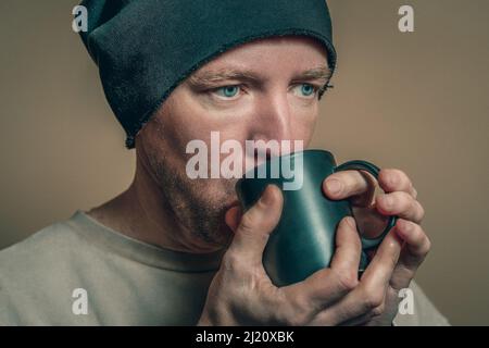 Porträt eines Mannes in einem schwarzen Hut mit einer schwarzen Tasse, Nahaufnahme Stockfoto