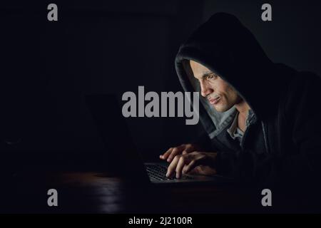 Schützen Sie sich, bevor es zu spät ist. Aufnahme eines verdunkelten Computerhackers mit einem Laptop im Dunkeln. Stockfoto