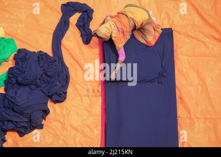 Narayanganj, Dhaka, Bangladesch. 29. März 2022. In Narayanganj, Bangladesch, sortieren Arbeiter bunte Stoffstapel, die zu Kleidungsstücken verarbeitet werden. Die Arbeiter sortieren und wählen die Stoffe nach Farbe, Qualität und der Nachfrage der Käufer aus. Die Stoffe werden in der Regel bei der Herstellung von Bekleidung verwendet. Sie werden für die Sortierung und Sortierung sowie zum Trocknen in der Sonne aufgeschichtet, wobei Feuchtigkeit aus dem Sterbeprozess entfernt wird. (Bild: © Joy Saha/ZUMA Press Wire) Stockfoto