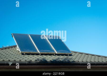 Drei Sonnenkollektoren auf dem Dach und blauen Himmel montiert Stockfoto