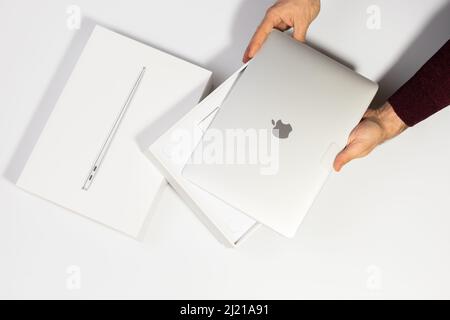 Saratov, Russland - 26. Februar 2022: Demonstration des neuen silbernen Macbook Air 13 Zoll mit M1 Prozessor und Verpackung flach liegend, weißer Hintergrund Stockfoto