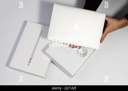 Saratov, Russland - 26. Februar 2022: Demonstration des neuen silbernen Macbook Air 13 Zoll M1-Prozessors und der Verpackung mit Ladefunktion, weißem Hintergrund Stockfoto