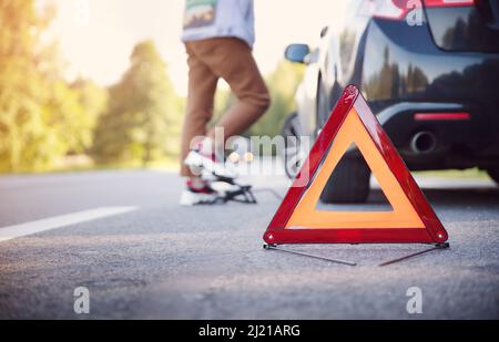 Frau pumpt das Rad des Autos am Straßenrand hoch Stockfoto