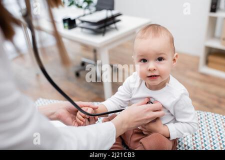 Verschwommener Hausarzt untersucht Kind mit Stethoskop in der Klinik Stockfoto