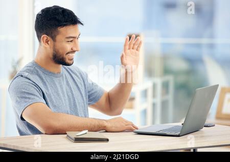 Lächelnd und winkend. Aufnahme eines jungen Geschäftsmannes bei einem Videoanruf in einem Büro bei der Arbeit. Stockfoto