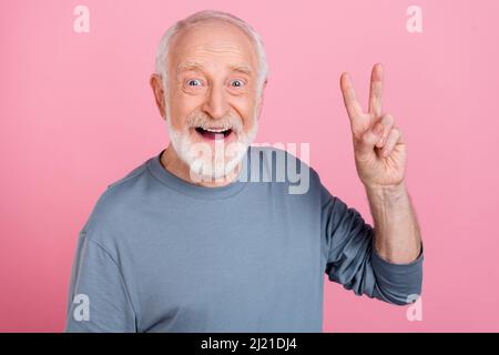 Foto von lustig beeindruckt Ruhestand Mann grau Pullover mit V-Zeichen isoliert rosa Hintergrund Stockfoto