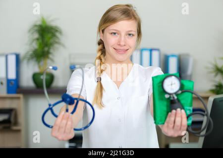 Die Krankenschwester hält ein Stethoskop und eine Blutdruckmanschette nach vorne Stockfoto