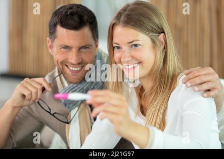 Glückliche junge Frau und Mann nach positivem Schwangerschaftstest Stockfoto