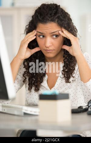 Die junge Frau im Büro ist müde und fühlt sich gestresst Stockfoto