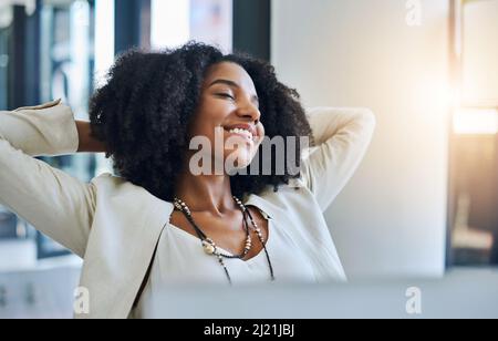Endlich kann ich die Pause machen, die ich verdient habe. Aufnahme einer jungen Geschäftsfrau, die sich an ihrem Schreibtisch entspannt. Stockfoto
