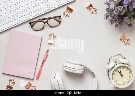 Draufsicht auf den Arbeitsplatz. Notepad Tastaturen Wecker Brille Kopfhörer auf dem Tisch. Stockfoto