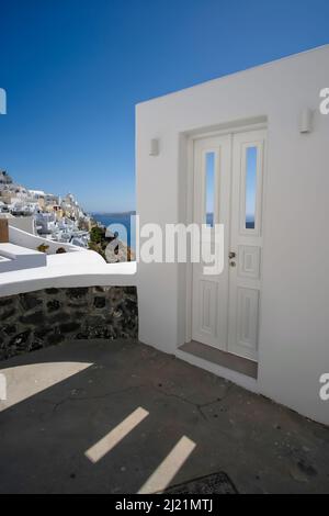 Typische Design weiße Dekoration Tür neben einer Gasse mit einem atemberaubenden Blick auf das Dorf Fira und die ägäis in Santorini Stockfoto