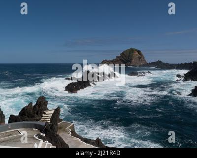 Atlantische Wellen schlagen über der vulkanischen felsigen Küste von Porto Moniz, einer bezaubernden Stadt an der Nordwestspitze von Madeira, Portugal EU Stockfoto