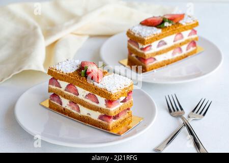 Erdbeerkuchen auf weißem Hintergrund. Geschichtete Torte mit Creme und Erdbeere. Nahaufnahme Stockfoto