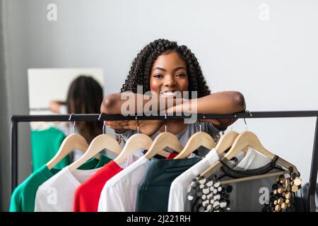 Afro-junge Frau, die in der Nähe ihres Kleiderschranks steht und darüber nachdenkt, was sie anziehen soll Stockfoto