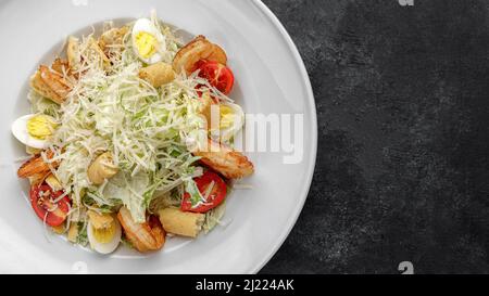 Caesar Salat mit Garnelen, auf dunklem Hintergrund. Stockfoto