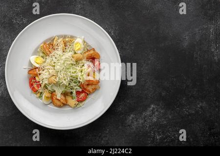 Caesar Salat mit Garnelen, auf dunklem Hintergrund. Stockfoto