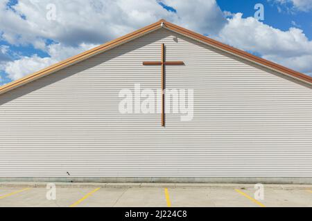 Ein großes Kreuz an der Außenwand einer Kirche in einer Kleinstadt. Stockfoto
