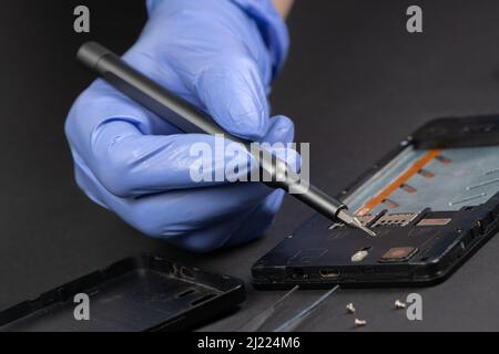 Reparatur von Mobiltelefonen. Hände eines Servicearbeiters, der modernes Mobiltelefon repariert. Stockfoto