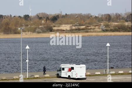 Rostock, Deutschland. 29. März 2022. Gegenüber dem Stadthafen an der Warnow soll auf dem Gelände einer versiegelten Deponie der Stadtpark für die Bundesgartenschau 2025 in Rostock errichtet werden; die beiden Seiten des Flusses sollen durch eine Fußgängerbrücke miteinander verbunden werden. Die im April 2025 geplante Eröffnung der Bundesgartenschau in Rostock scheint in Gefahr zu sein. Neben den bereits bestehenden Problemen gibt es nun die stark steigenden Baukosten und die Rohstoffkrise. Quelle: Bernd Wüstneck/dpa-Zentralbild/dpa/Alamy Live News Stockfoto