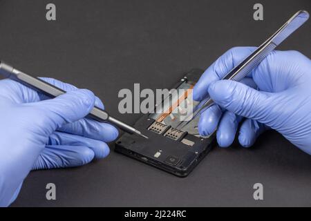 Reparatur von Mobiltelefonen. Hände eines Servicearbeiters, der modernes Mobiltelefon repariert. Stockfoto