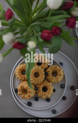 Mini-Bunt-Kuchen mit Früchten auf dem Teller und einem Bouquet von Tulpen. Frühstück Stockfoto