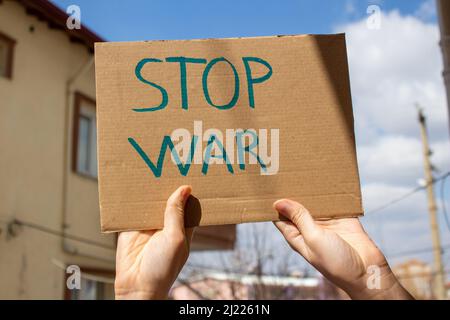 Hand hält das geschriebene Plakat „Stop war“. Demonstration gegen den Krieg. Stockfoto