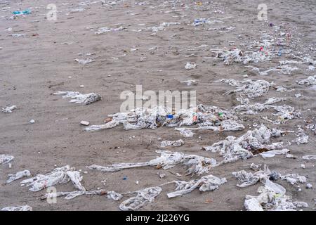 Strand voller Müll, nasser Tücher und Abfall, den die Leute in die Toilette werfen. Konzept der Meeresverschmutzung und Umweltzerstörung Stockfoto
