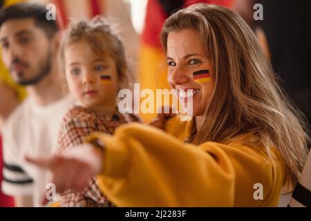 Begeisterte Fußballfans, Mutter mit kleiner Tochter, die die deutsche Nationalmannschaft in einem Live-Fußballspiel im Stadion unternahmen. Stockfoto