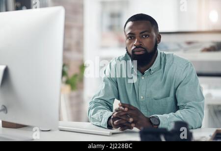 Nehmen Sie Ihre Zukunft ernst. Aufnahme eines hübschen jungen Geschäftsmannes, der allein in seinem Büro sitzt und seinen Computer benutzt. Stockfoto