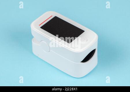 Modernes Pulsoximeter mit Fingerspitzen, isoliert auf blauem Hintergrund. Stockfoto