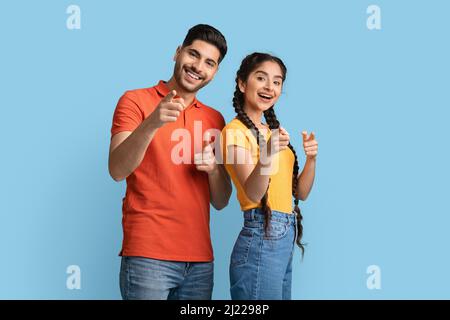 Positiver Mann und Frau aus dem Nahen Osten zeigen mit den Fingern auf die Kamera Stockfoto