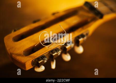Das Griffbrett einer alten Vintage-Gitarre mit Metallsaiten an einem sonnigen Tag. Ein Musikinstrument. Erstellung. Solfeggio. Stockfoto